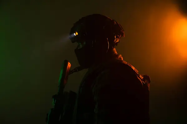 Üniformalı asker. Yüksek kaliteli 4K görüntüler. Tam teçhizatlı kararlı bir asker dumanlı, atmosferik bir sahnede yürüyor. Yoğun ve renkli ışıklandırmayla aydınlatılıyor.. 