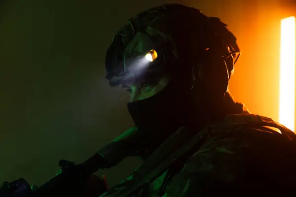 Üniformalı asker. Yüksek kaliteli 4K görüntüler. Tam teçhizatlı kararlı bir asker dumanlı, atmosferik bir sahnede yürüyor. Yoğun ve renkli ışıklandırmayla aydınlatılıyor.. 