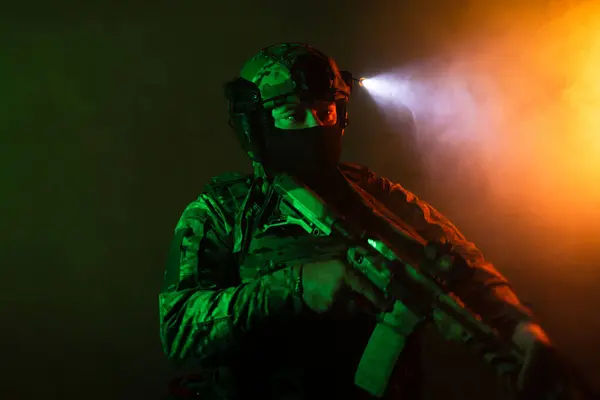 Üniformalı asker. Yüksek kaliteli 4K görüntüler. Tam teçhizatlı kararlı bir asker dumanlı, atmosferik bir sahnede yürüyor. Yoğun ve renkli ışıklandırmayla aydınlatılıyor.. 