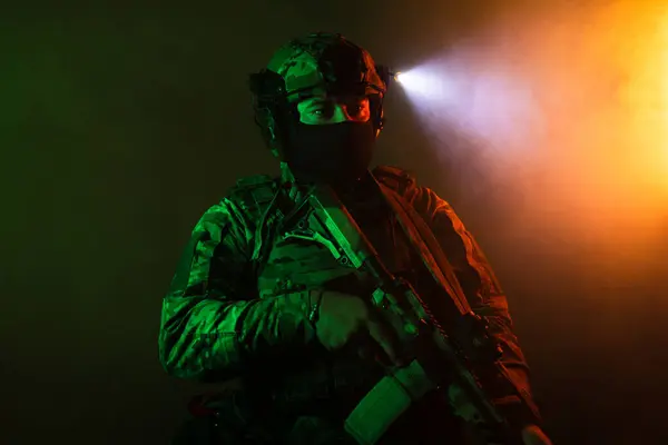 Üniformalı asker. Yüksek kaliteli 4K görüntüler. Tam teçhizatlı kararlı bir asker dumanlı, atmosferik bir sahnede yürüyor. Yoğun ve renkli ışıklandırmayla aydınlatılıyor.. 