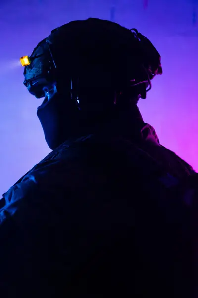 Üniformalı asker. Yüksek kaliteli 4K görüntüler. Tam teçhizatlı kararlı bir asker dumanlı, atmosferik bir sahnede yürüyor. Yoğun ve renkli ışıklandırmayla aydınlatılıyor.. 