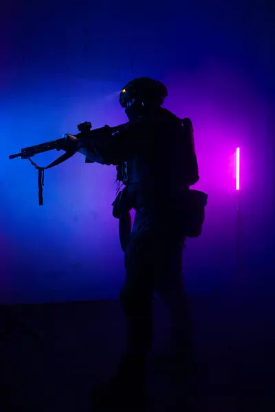 Üniformalı asker. Yüksek kaliteli 4K görüntüler. Tam teçhizatlı kararlı bir asker dumanlı, atmosferik bir sahnede yürüyor. Yoğun ve renkli ışıklandırmayla aydınlatılıyor.. 