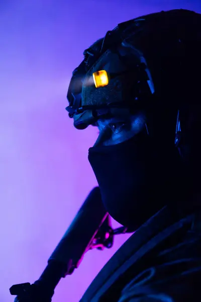 Üniformalı asker. Yüksek kaliteli 4K görüntüler. Tam teçhizatlı kararlı bir asker dumanlı, atmosferik bir sahnede yürüyor. Yoğun ve renkli ışıklandırmayla aydınlatılıyor.. 