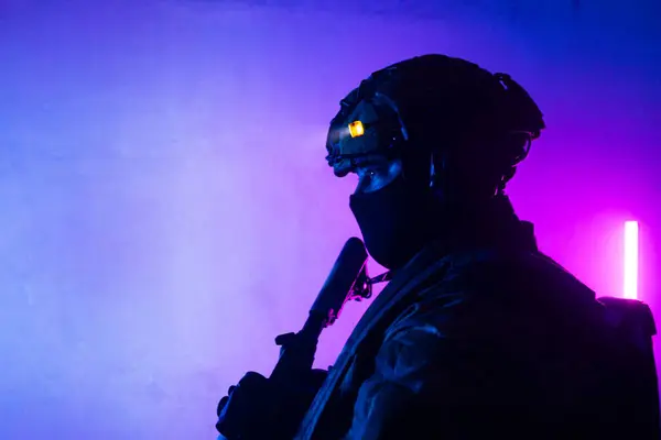 Üniformalı asker. Yüksek kaliteli 4K görüntüler. Tam teçhizatlı kararlı bir asker dumanlı, atmosferik bir sahnede yürüyor. Yoğun ve renkli ışıklandırmayla aydınlatılıyor.. 