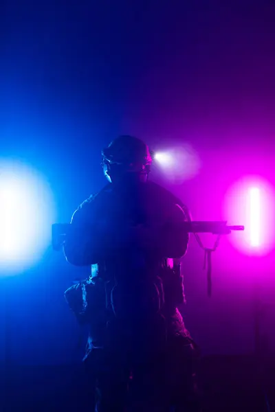 Üniformalı asker. Yüksek kaliteli 4K görüntüler. Tam teçhizatlı kararlı bir asker dumanlı, atmosferik bir sahnede yürüyor. Yoğun ve renkli ışıklandırmayla aydınlatılıyor.. 