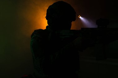 Üniformalı asker. Yüksek kaliteli 4K görüntüler. Tam teçhizatlı kararlı bir asker dumanlı, atmosferik bir sahnede yürüyor. Yoğun ve renkli ışıklandırmayla aydınlatılıyor.. 