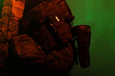 Üniformalı asker. Yüksek kaliteli 4K görüntüler. Tam teçhizatlı kararlı bir asker dumanlı, atmosferik bir sahnede yürüyor. Yoğun ve renkli ışıklandırmayla aydınlatılıyor.. 