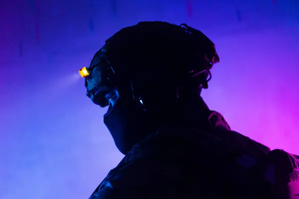 Üniformalı asker. Yüksek kaliteli 4K görüntüler. Tam teçhizatlı kararlı bir asker dumanlı, atmosferik bir sahnede yürüyor. Yoğun ve renkli ışıklandırmayla aydınlatılıyor.. 