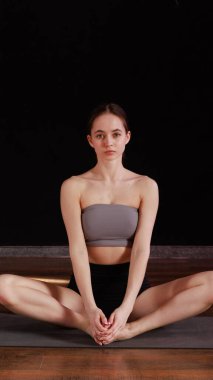 Yoga ve esneme hareketi Low Lunge PoseA 'da genç bir kadın yoga yapıyor ve kapalı alanda esniyor koyu gri bir paspasın üzerinde.. 