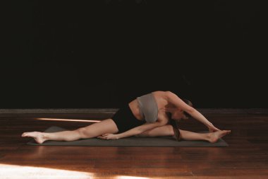 Yoga ve esneme hareketi Low Lunge PoseA 'da genç bir kadın yoga yapıyor ve kapalı alanda esniyor koyu gri bir paspasın üzerinde.. 