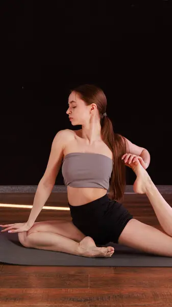 Yoga ve esneme hareketi Low Lunge PoseA 'da genç bir kadın yoga yapıyor ve kapalı alanda esniyor koyu gri bir paspasın üzerinde.. 