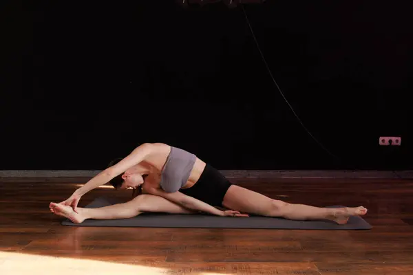 Yoga ve esneme hareketi Low Lunge PoseA 'da genç bir kadın yoga yapıyor ve kapalı alanda esniyor koyu gri bir paspasın üzerinde.. 