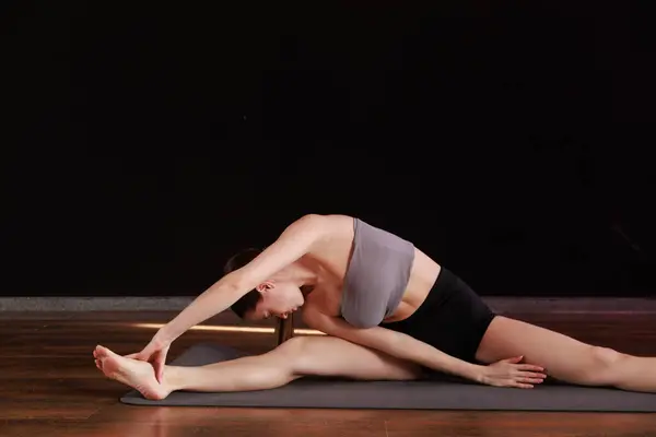Yoga ve esneme hareketi Low Lunge PoseA 'da genç bir kadın yoga yapıyor ve kapalı alanda esniyor koyu gri bir paspasın üzerinde.. 