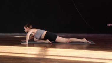 Yoga ve esneme hareketi Low Lunge PoseA 'da genç bir kadın yoga yapıyor ve kapalı alanda esniyor koyu gri bir paspasın üzerinde.. 