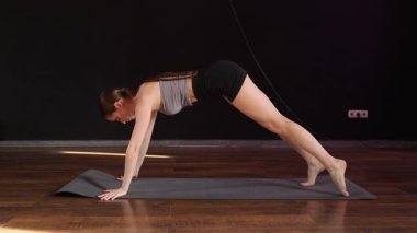 Yoga ve esneme hareketi Low Lunge PoseA 'da genç bir kadın yoga yapıyor ve kapalı alanda esniyor koyu gri bir paspasın üzerinde.. 