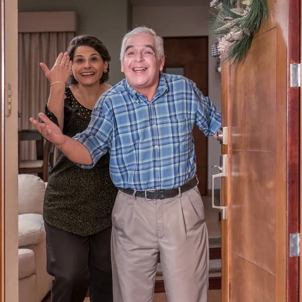 happy senior grandparents near door in house.