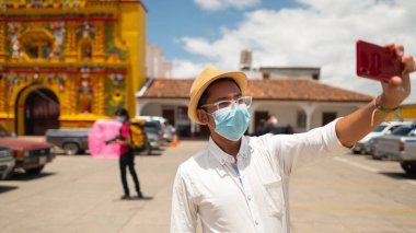 Close-up view of a man in a hat with a medical mask taking a selfie.
