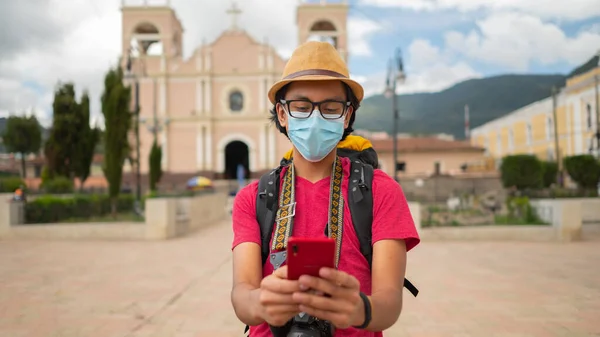 Portrait of a young man writing a message on his cell phone and a church on the background.