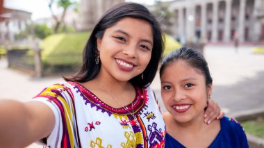 Portrait of two friends taking a selfie with the cell phone in the park of Quetzaltenango.