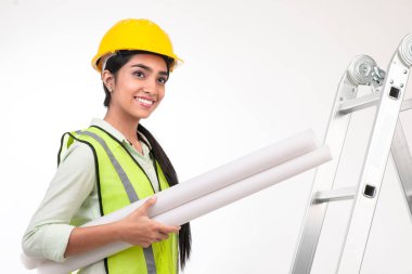 Female architect holding blueprints, smiling, Looking at the horizon.
