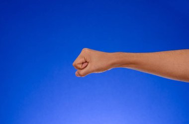 Hand clenched tightly on blue background