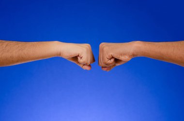 Fists of two people clashing, on a blue background