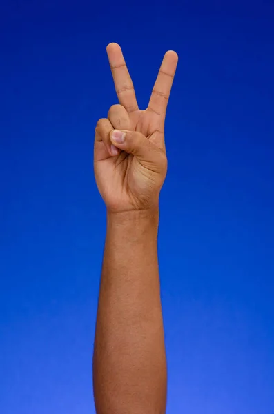 Hand making sign of love and peace on blue background