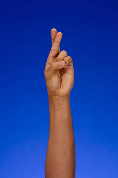 Fingers crossed as a symbol of luck. arms and palms making signs on a blue background