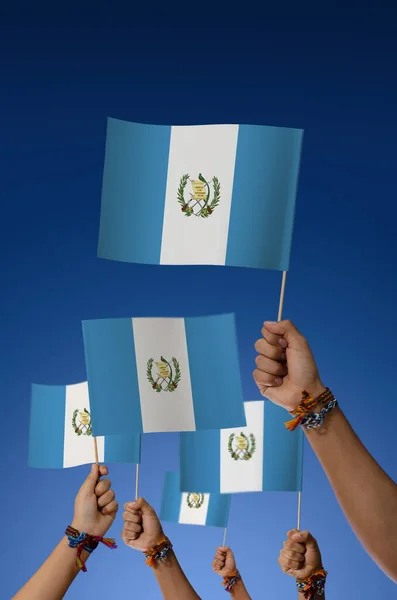 Group of young people holding Guatemala flags on blue background
