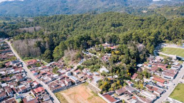 Latin Amerika 'da ormanlarla ve dağlarla çevrili bir kasabanın havadan görünüşü..