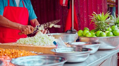 Büyük bir bıçakla lahana doğrayan bir adam. Limonlar kasede.