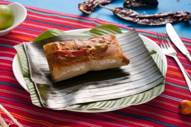 Muz yapraklı kırmızı tamale. Etrafında renklerden ve malzemelerden oluşan güzel bir atmosfer.