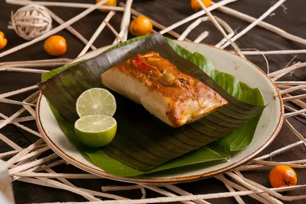 Muz yapraklarıyla kaplı seramik tabağın güzel bileşimi ve üstünde mısır tamale..