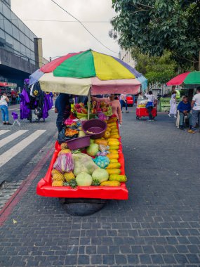 Guatemala, Guatemala / Guatemala-19 Nisan 2023: Bir meyve satıcısı ürünlerini el yapımı ahşap bir arabada sergiliyor. Yaz güneşini hafifletmek için arabasına bir şemsiye ekledi..