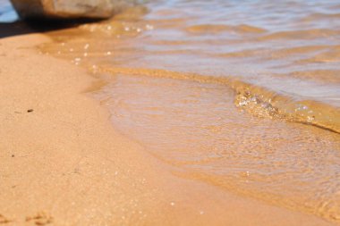 Kumsalda kumsala ulaşan temiz su dalgaları.