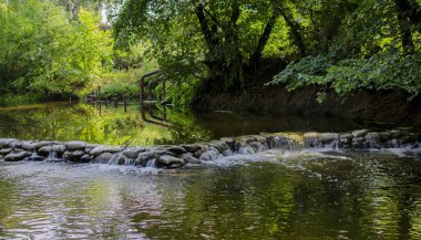 Borovaya nehri üzerinde, yeşil ağaçlarla çevrili, kır evi su pompasının yanındaki kum torbalarından yapılmış pitoresk bir baraj..