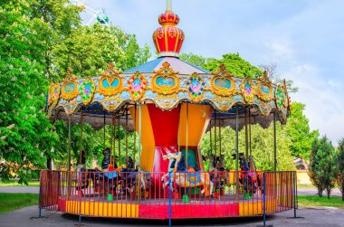 Bir lunaparkta renkli süslemeleri olan canlı bir atlıkarınca çocuklar için neşeli bir deneyim sunuyor..