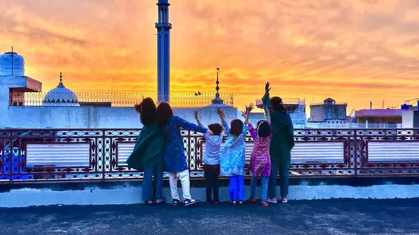 Çocuklar yağmurdan sonra güneşin batışının tadını çıkarıyorlar 