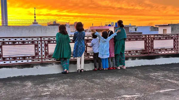 Çocuklar yağmurdan sonra güneşin batışının tadını çıkarıyorlar 