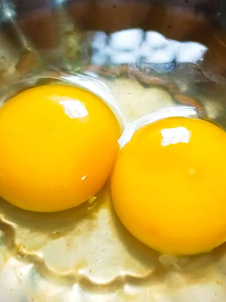 Bir yumurta iki yumurta sarısı ile kırılmış. İkisi de yuvarlak ve sarı. Özel ve şaşırtıcı görünüyor.