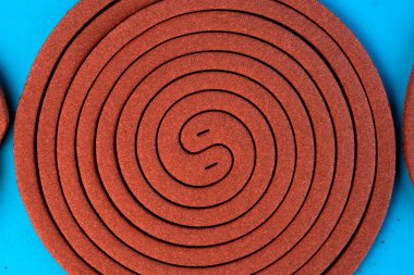 Mavi arka planda sarmal şeklinde kahverengi bir sivrisinek bobini. Sivrisinekleri uzak tutmak ve ısırıklardan korunmak için tasarlanmış, açık ve kapalı alan kullanımı için böcek kovucu..