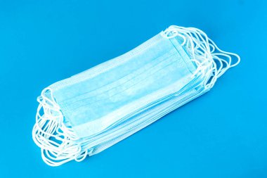 Parlak mavi arka planda beyaz elastik kulak halkaları olan tek kullanımlık mavi yüz maskeleri. Koruyucu maskeler sağlık, hijyen ve güvenlik için gereklidir..