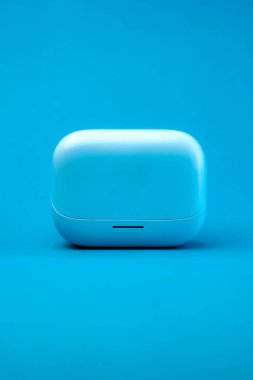 Modern bir kablosuz kulaklık parlak mavi bir tasarımla şarj edilmiş, parlak mavi bir arka planda izole edilmiş. Kompakt, hafif ve şık, seyahat ve günlük kullanım için mükemmel.