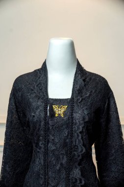 Zarif siyah dantelli kebaya yakın plan, altın kelebek broşu ile süslenmiş, geleneksel Endonezya modasını zarif detaylar ve sonsuz karmaşıklıkla gözler önüne seriyor..