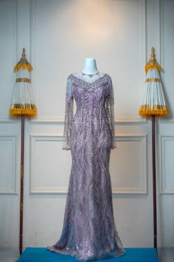 Zarif leylak gece elbisesi, karmaşık detaylar ve pullu desenler, kültürel aksanlı lüks bir iç mekanda sergilenen bir manken üzerinde sergileniyor..