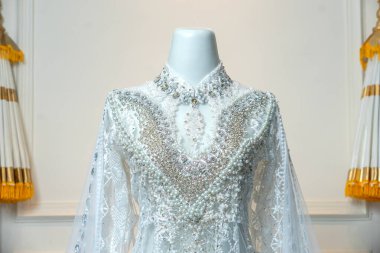 Şık, beyaz bir gelinliğin yakın çekimi. Detaylı boncuklu, incili ve dantelli. Geleneksel akad nikah ya da zarif bir tören için mükemmel..