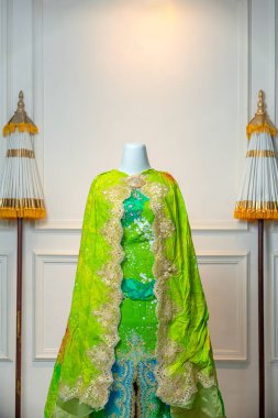 Parlak yeşil ve mavi geleneksel gelinlik, altın işlemeli ve süslü dantel detaylar, lüks gelinlik ve kültürel kutlama konsepti için mankenlerde sergileniyor..
