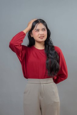 Uzun siyah saçlı Endonezyalı kadın sessiz sessiz bir jest yapıyor, parmakları dudaklarında, hafifçe öne eğiliyor, neşeli bir ifadeyle gülümsüyor.