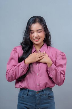 Uzun siyah saçlı, güzel bir Endonezyalı kadının portresi. Nazikçe gülümseyen gözleri ve elleri göğsünde. Minnettarlığını ve sıcaklığını ifade ediyor..