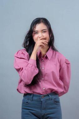 Uzun siyah saçlı, pembe bluz ve kot pantolon giyen Endonezyalı bir kadın utangaç bir gülümsemeyle stüdyoda durup ağzını kapatırken cazibesini, utangaçlığını ve masumiyetini gösteriyor..